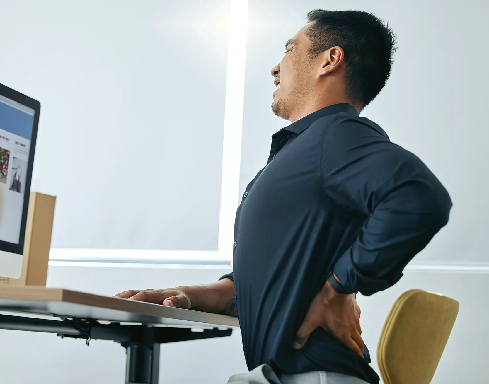 The importance of posture, man at workstation experiencing back pain